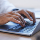 Side View Of Hands Typing On Computer