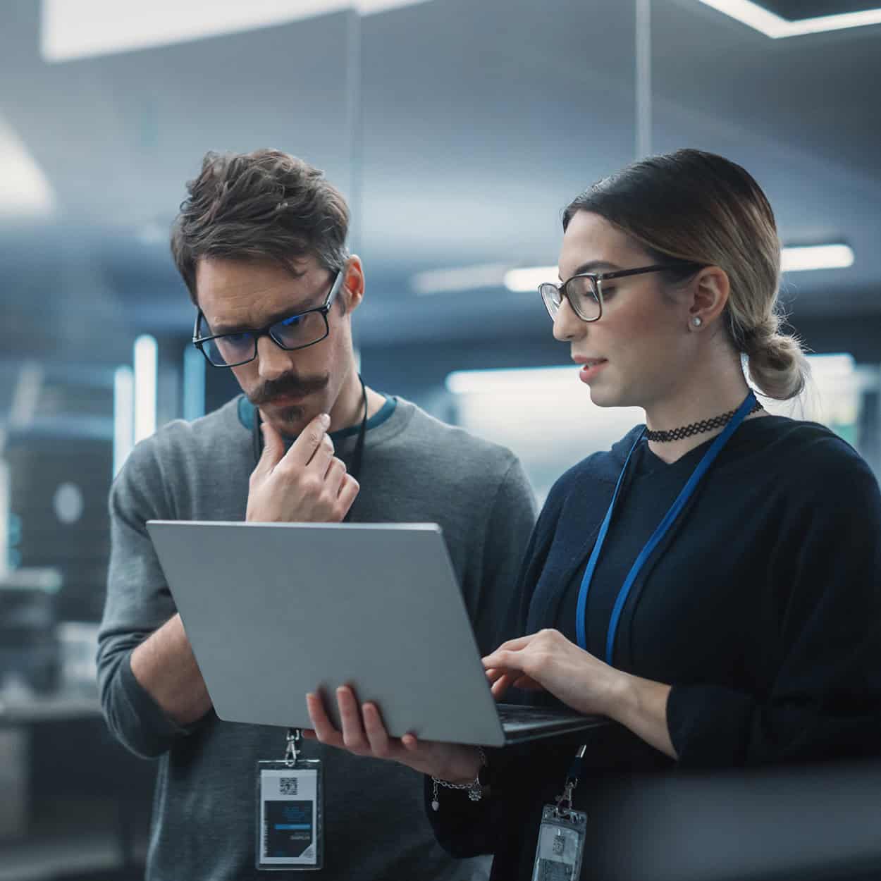 Header Side View Of Two Cybersecurity Professionals Looking At Laptop