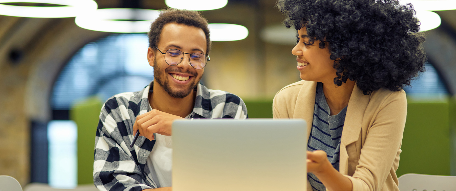 Two Smiling People Collaborating On Laptop