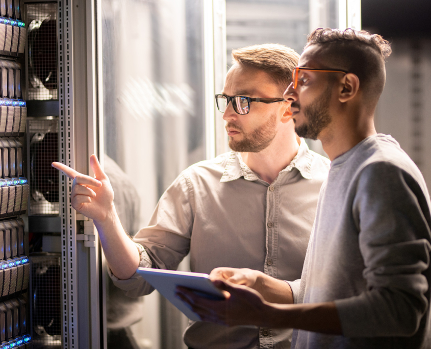 Side View Of Two Men Collaborating In Server Room