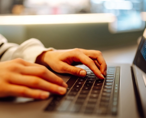 Close-up of hands working on a laptop keyboard